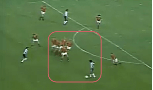 A picture taken from a different angle as the famous Maradona one, showing Maradona recieving the ball and the 6 players in the Belgium wall turned to look at him.